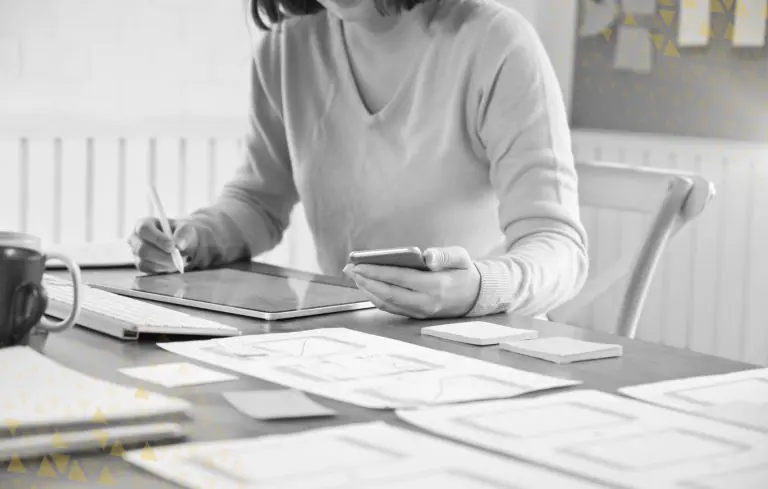 women on phone while working on design