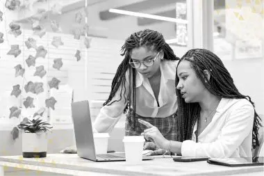 two woman looking at a computer at the office