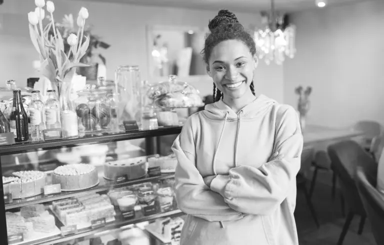 woman standing in front of case of cakes at bake shop