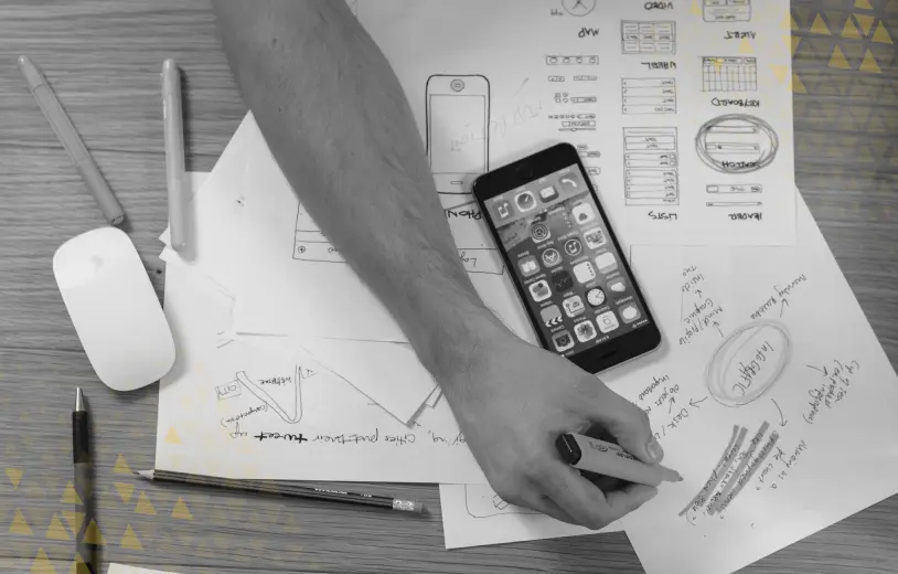 hand writing notes with smartphone laid on top of several ux drawings
