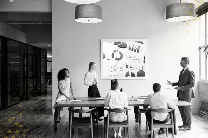 A meeting room scene where marketing and sales teams collaborate around a table, with ABM strategy charts visible in the background, symbolizing the teamwork essential for ABM success.